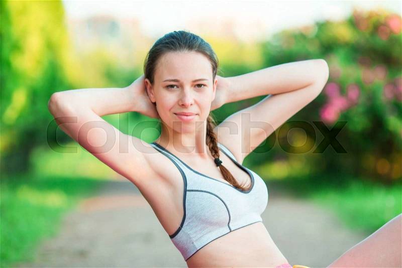 Fitness runner body closeup doing warm-up routine on beach before running, stretching leg muscles with standing single knee to chest stretch. Female athlete preparing legs for cardio workout, stock photo