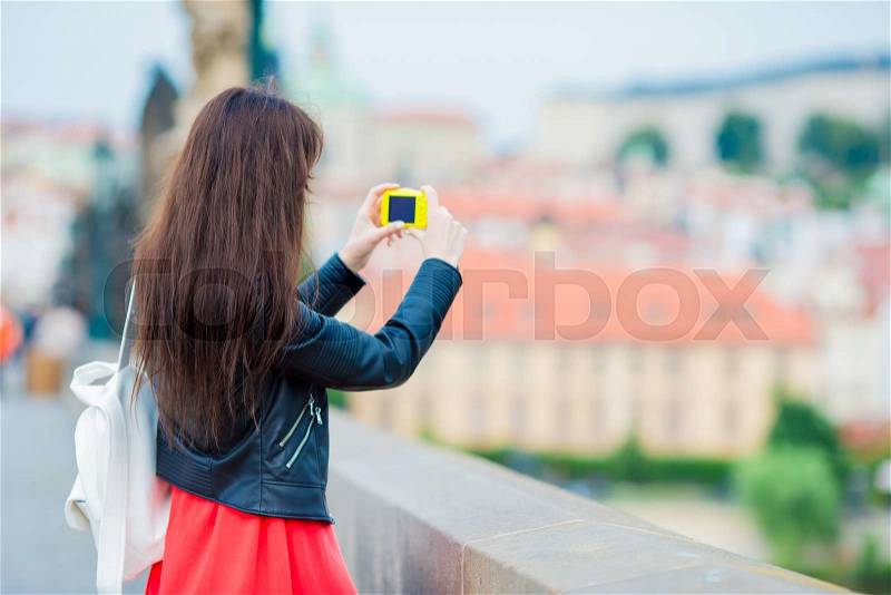 Tourist girl taking travel photos by famous attraction with smartphone on summer holidays. Young attractive tourist taking photo with mobile phone outdoors enjoying holidays travel destination in tourism and exploring concept, stock photo
