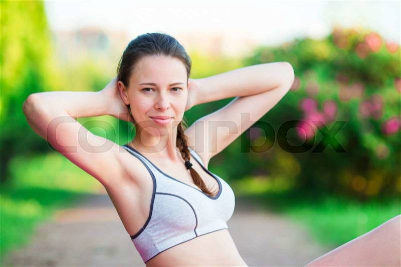 Fitness runner body closeup doing warm-up routine on beach before running, stretching leg muscles with standing single knee to chest stretch. Female athlete preparing legs for cardio workout, stock photo