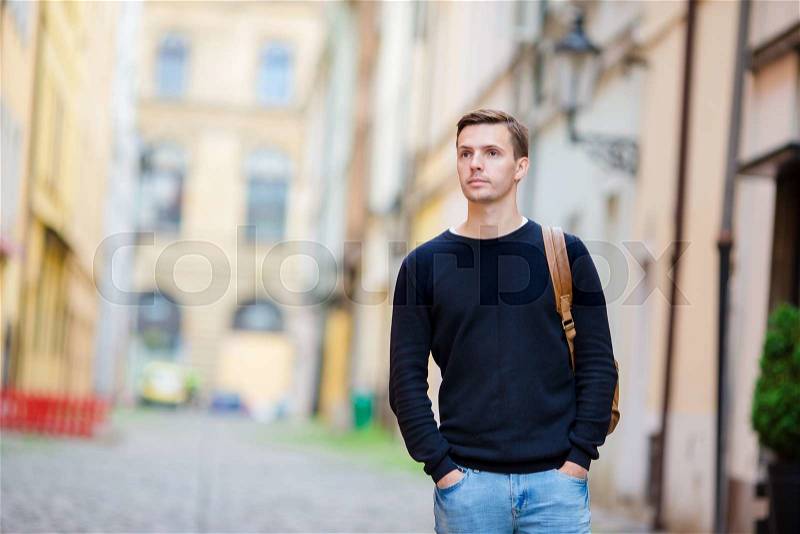 Caucasian tourist walking along the deserted streets of Europe. Young urban boy on vacation exploring european city cobblestone street, stock photo