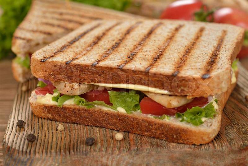 Sandwich with chicken and vegetables on a wooden background, stock photo