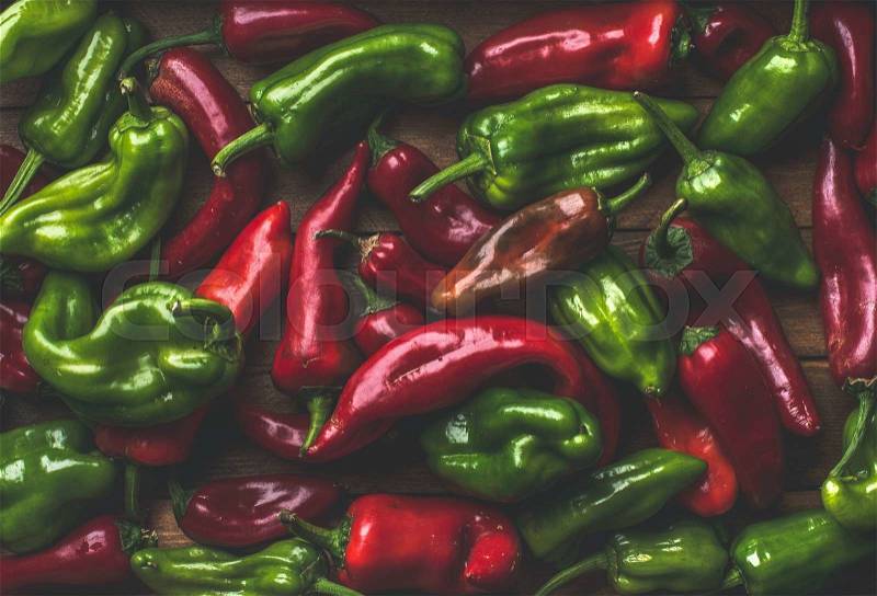 Background of colorful red and green bell peppers over wooden backdrop, top view, stock photo