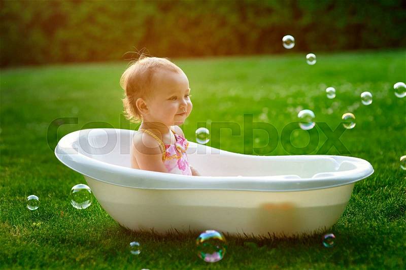 Little girl bathes in a bath with soap bubbles, stock photo