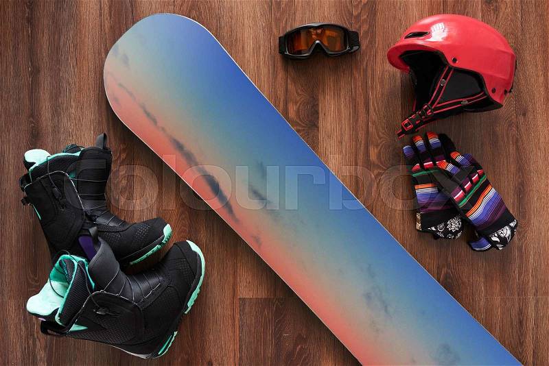 Set of snowboard equipment boots, helmet, gloves and mask on a wooden floor , stock photo