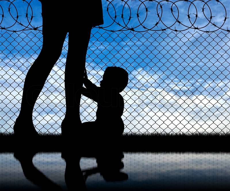 Refugee family concept. Silhouette of the child and refugee mothers legs near the fence of barbed wire, stock photo