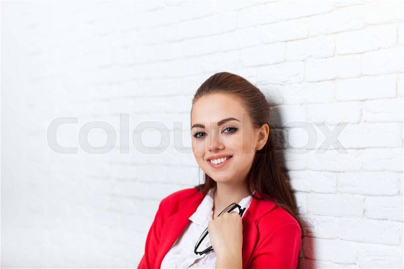 Businesswoman smiling face wear red jacket hold glasses business woman smile over office wall, stock photo