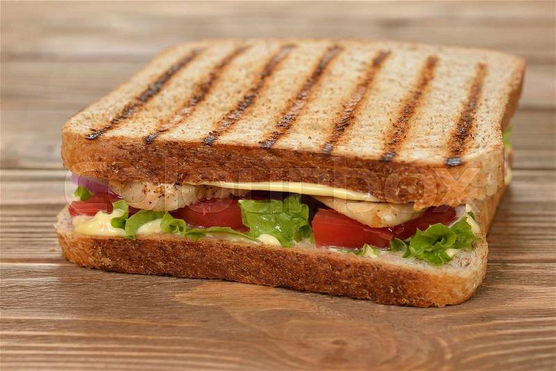 Sandwich with chicken and vegetables on a wooden background, stock photo