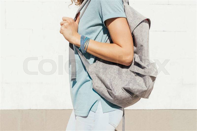 Slender girl with a backpack walking along the city in the summer, stock photo