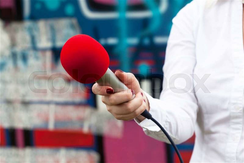 Journalist holding a microphone conducting an TV or radio interview, stock photo