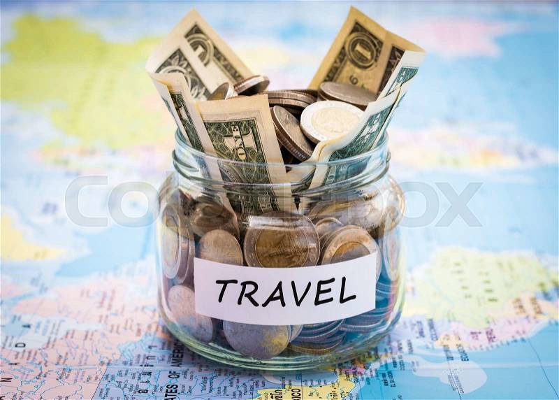 Travel budget concept. Travel money savings in a glass jar on world map, stock photo