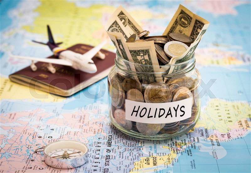 Holidays budget concept. Holidays money savings in a glass jar with compass, passport and aircraft toy on world map, stock photo