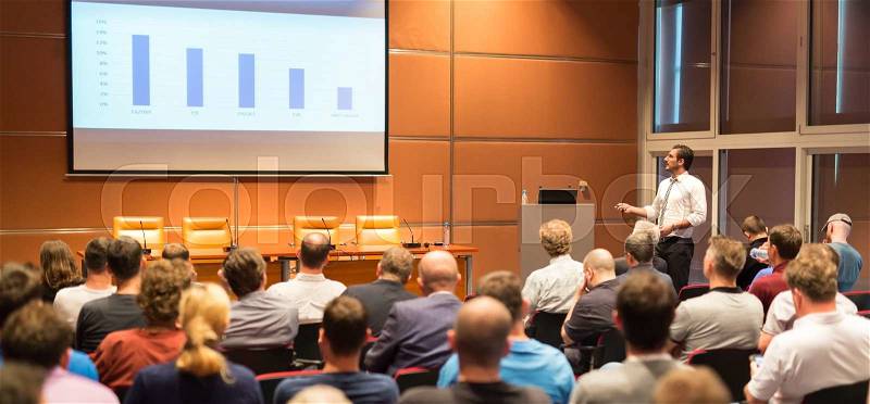 Speaker giving talk in conference hall at business event. Audience at the conference hall. Business and Entrepreneurship concept. Panoramic composition, stock photo