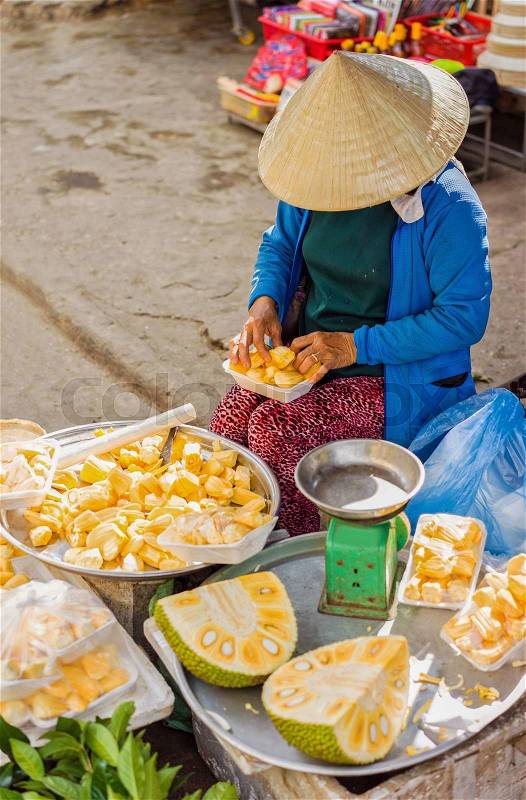 Asian woman in traditional hat selling flesh of fresh durian fruit just cleaned and packed in the streets in Hoi An, Vietnam, stock photo