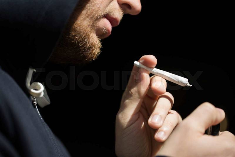 Drug use, substance abuse, addiction, people and smoking concept - close up of addict lighting up marijuana joint with lighter, stock photo