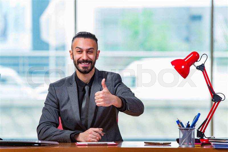 Man with his thumbs up in the office desk, stock photo