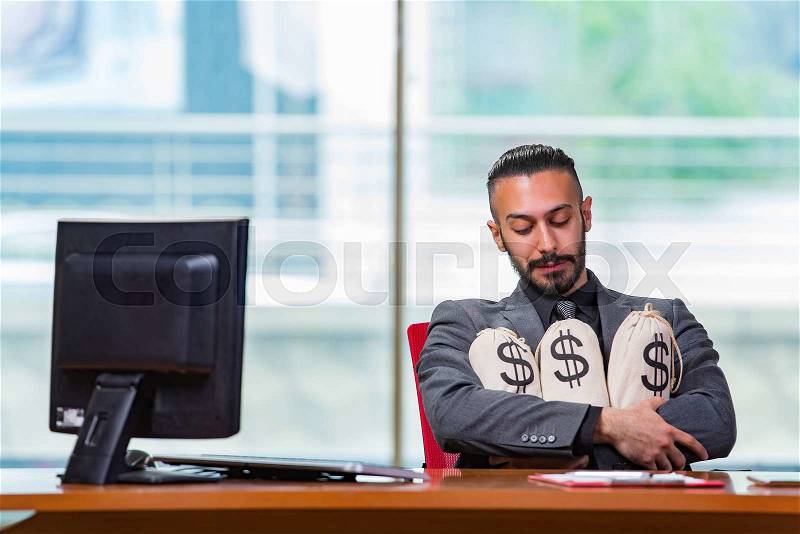 Happy businessman with money sacks in the office, stock photo