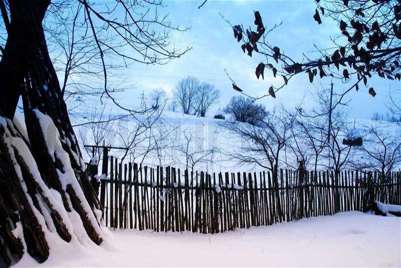 Rural winter mountain landscape with sundown and road, trees, fence, stock photo