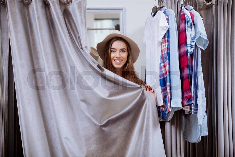 Cheerful young woman covered herself standing in fitting room, stock photo