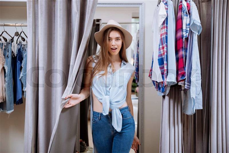 Happy young woman standing in fitting room in clothing store, stock photo