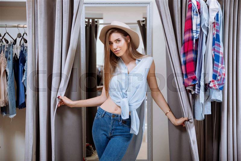 Portrait of beautiful young woman in dressing room of clothing shop, stock photo