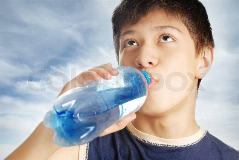 Drinking boy and bottle with mineral water after sport game, stock photo
