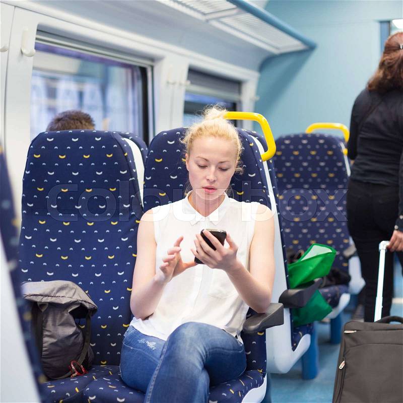 Woman workin on smart phone while traveling by train. Business travel concept, stock photo