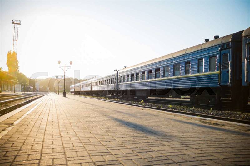 Railway platform and a train in the sun backlight, travel background, stock photo