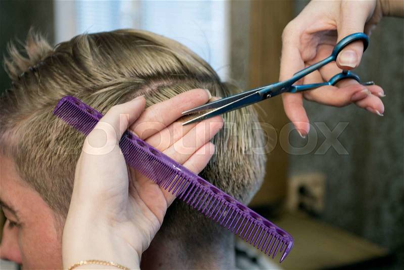 Barbershop. Close up woman\'s hands making man\'s haircut with scissors and a comb, stock photo
