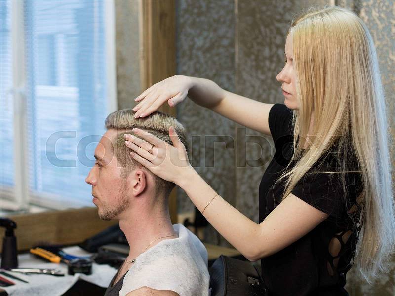 Barbershop. Woman barber making man\'s haido, side view, stock photo
