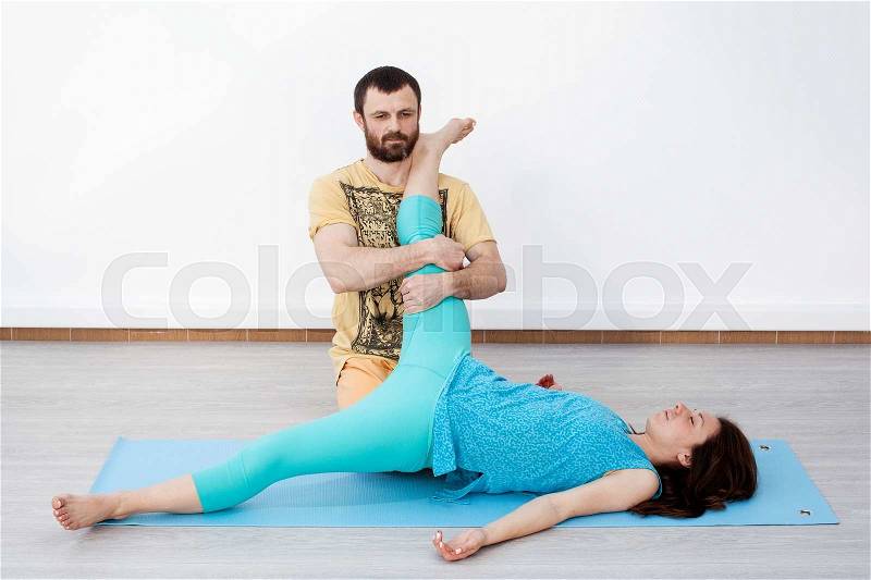 Pair exercises. Man performing thai massage, strtetching woman\'s leg, stock photo