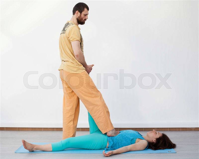 Pair exercises. Stretching. Man performing thai massage, srtetching woman\'s leg, presses on her stomach, stock photo