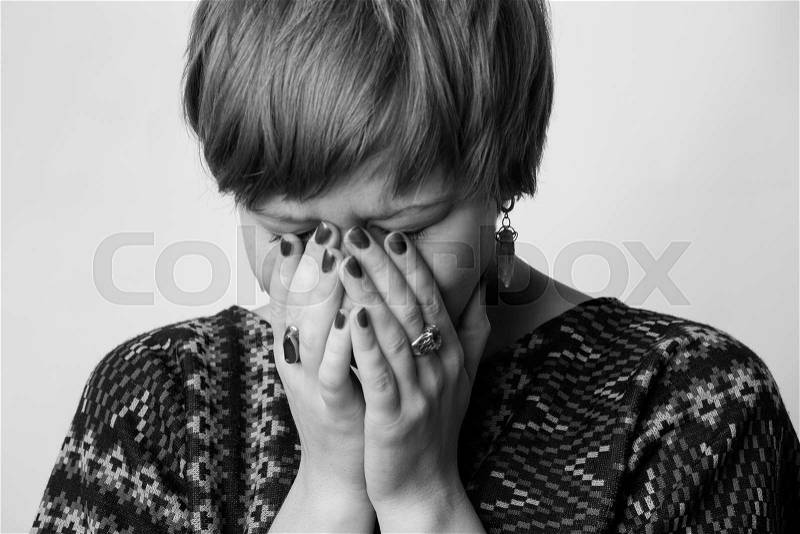 Crying woman , her face is hidden in the hands. Black and white image, stock photo