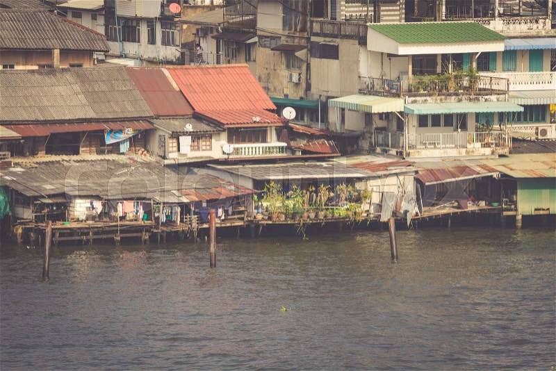 Wooden slums on stilts on the riverside of Chao Praya River in Bangkok, Thailand, stock photo