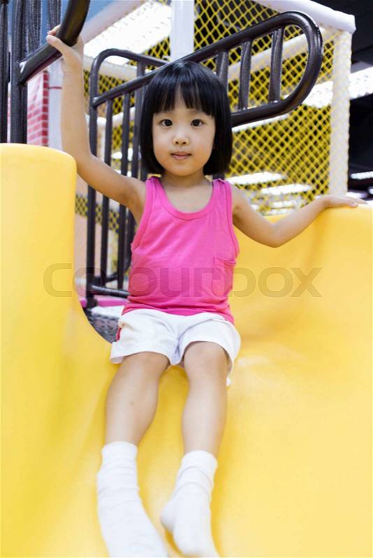 Asian Chinese Little Girl Playing on the Slide at Indoor Colourful Playground, stock photo