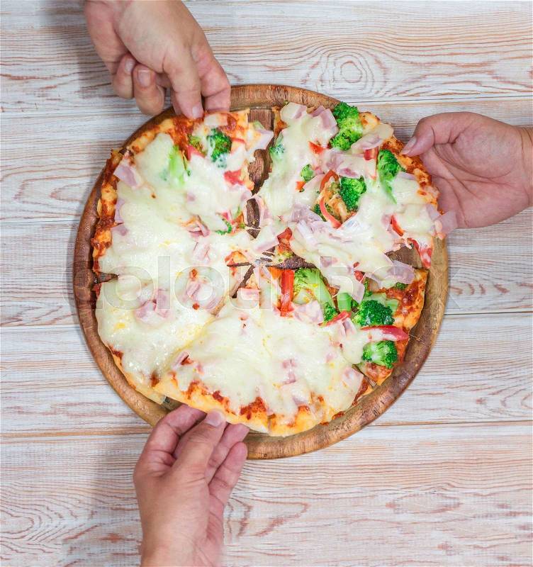 Friends hands taking slices of pizza. Top view on wood\, stock photo