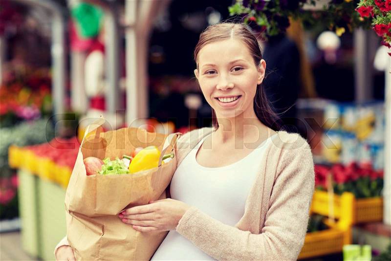 Sale, shopping, pregnancy and people concept - happy pregnant woman with paper bag full of food at street market, stock photo