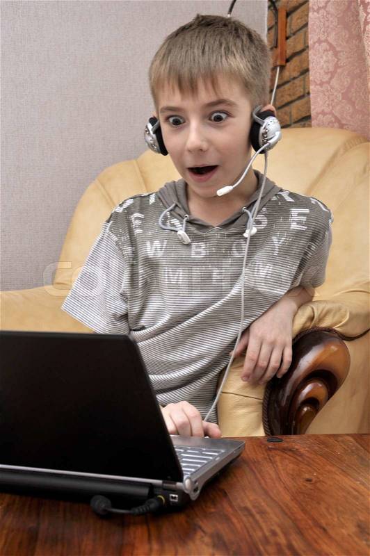 Surprised Boy Working On Laptop Computer at home, stock photo