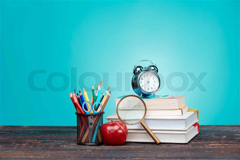 Back to School concept.School Books, colored pencils and clock on blue background, stock photo