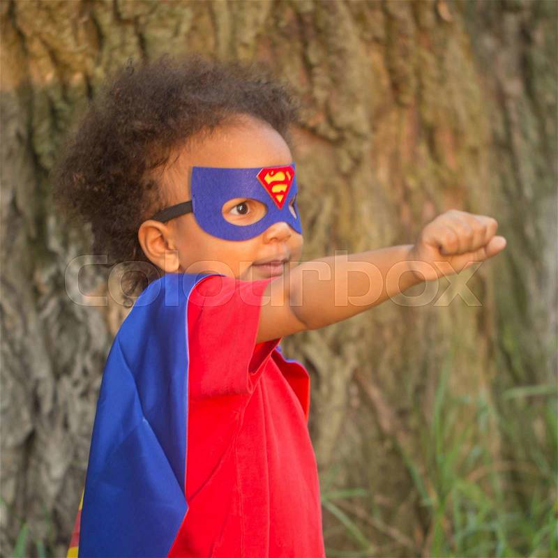 Black baby in superhero costume. Child playing in the park. The winner and success concept, stock photo