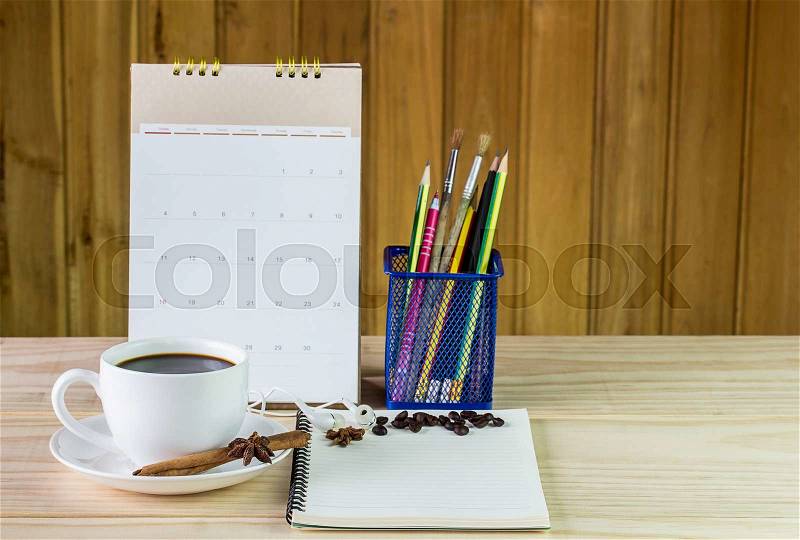 Coffee cup,and note book with calendar on wooden table background. Business concept, stock photo
