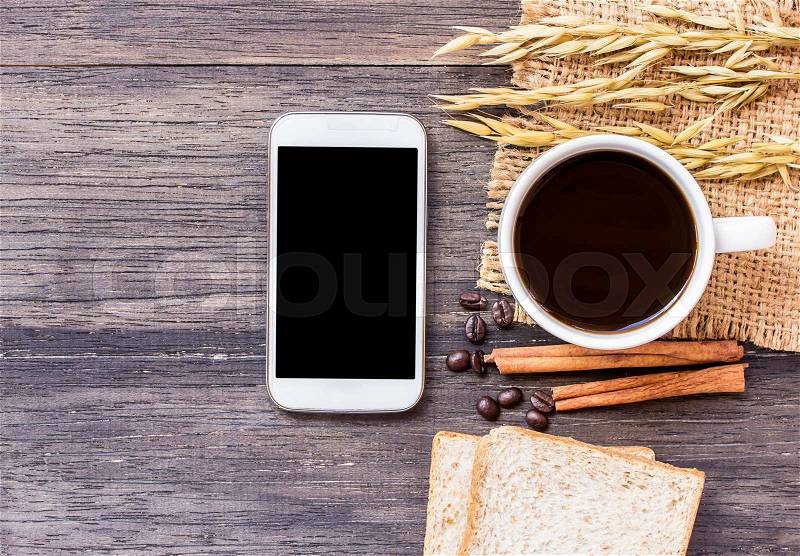 Ears of wheat,smart phone and coffee with slice of bread on a dark wooden table background.top view with copy space, stock photo