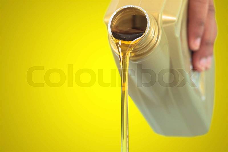 Motor oil pouring on yellow background, stock photo
