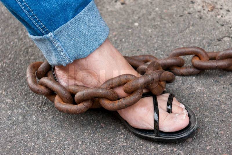 Woman foot chained with very thick and rusty chain, stock photo