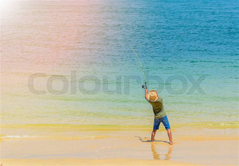 Young boy fishing rod on sunny beach, stock photo