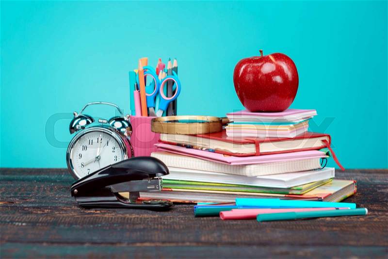 Back to School concept. Books, colored pencils and clock on blue background, stock photo