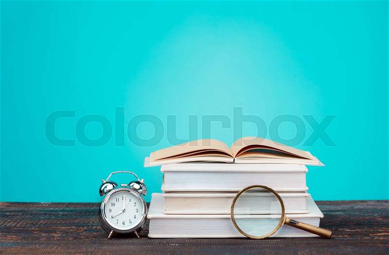 Back to School concept. School Books, colored pencils and clock on blue background, stock photo