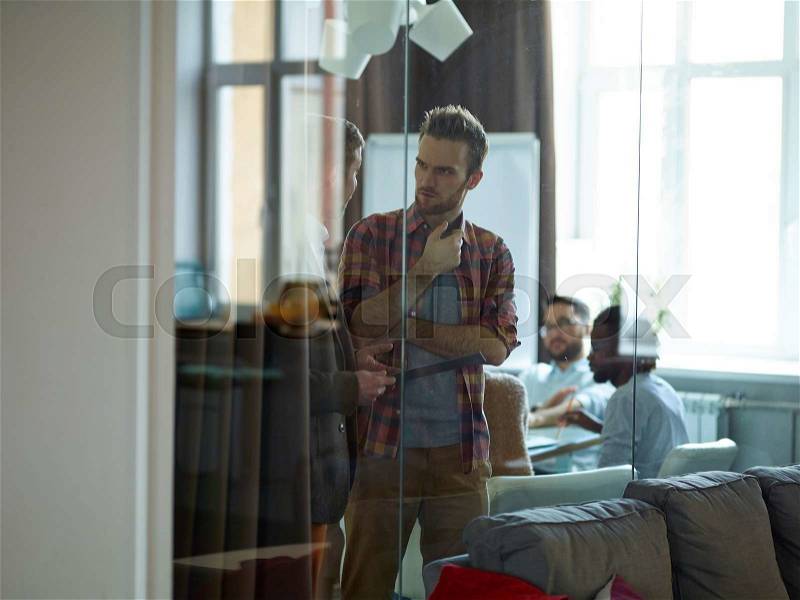 Two young businessmen having conversation in office, stock photo