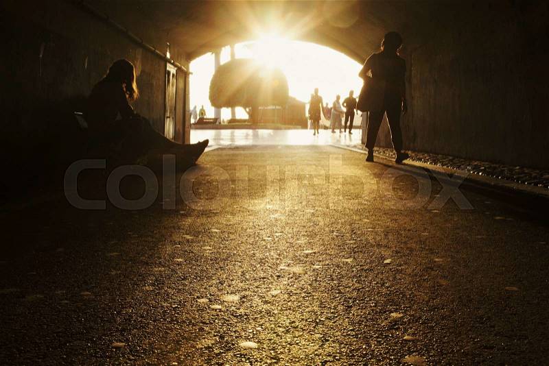 Tunnel in modern city with street artist and passerbies on sunny day, stock photo