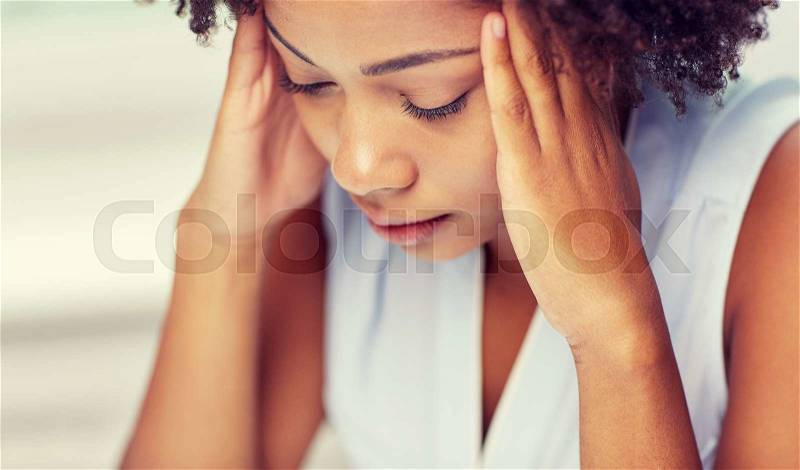 People, emotions, stress and health care concept - unhappy african american young woman touching her head and suffering from headache, stock photo