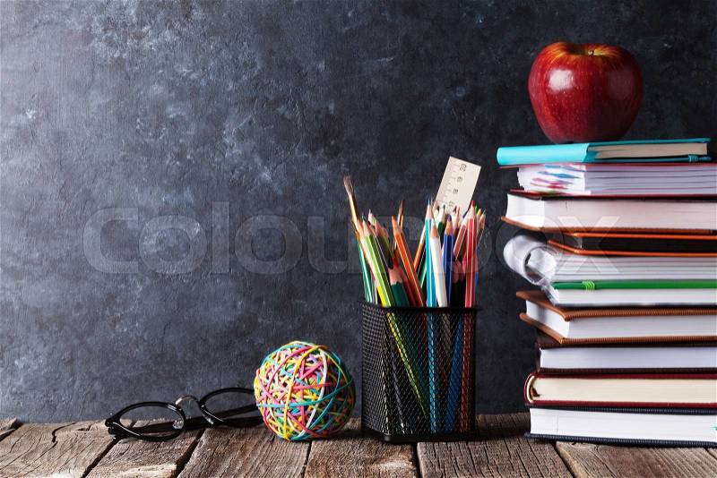 Notepads, supplies and glasses in front of chalk board. Back to school concept with copy space, stock photo